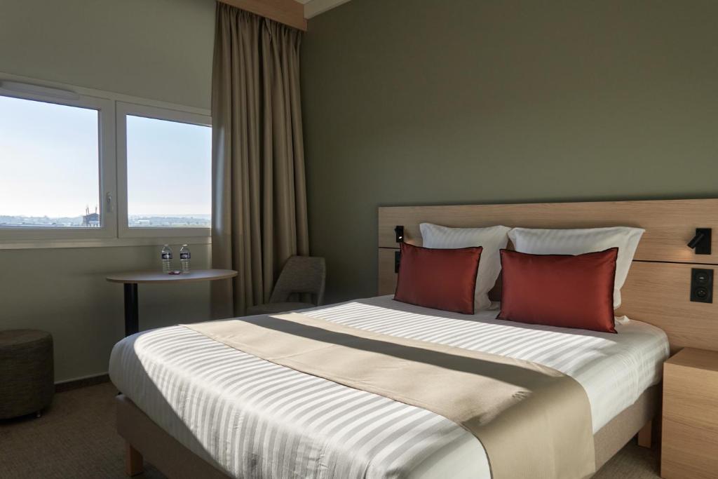 a bedroom with a large bed with red pillows at Hôtel Akena Troyes - La Chapelle St-Luc in Troyes