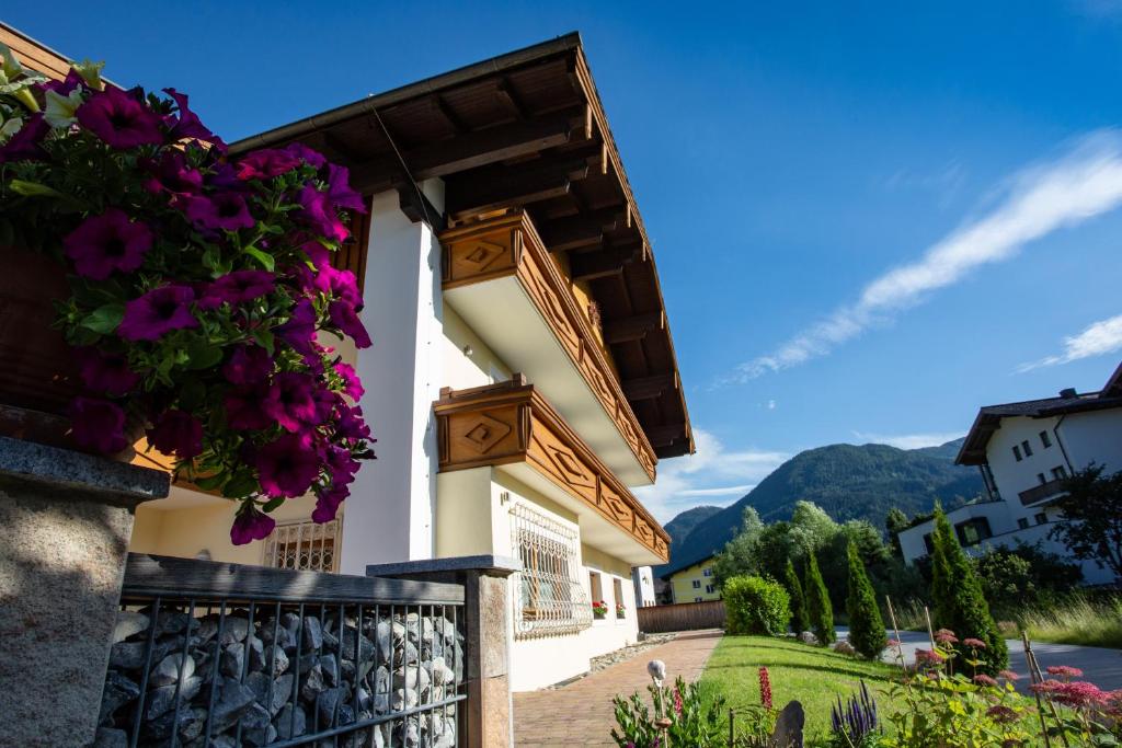 a house with purple flowers on a fence at Stangl Appartements in Flachau