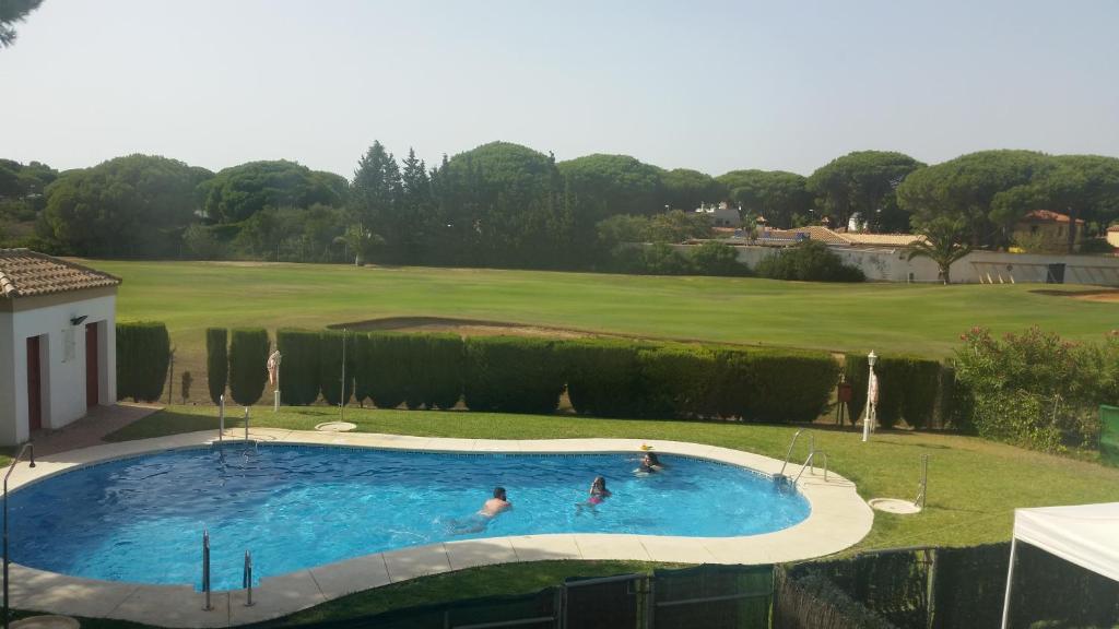 dos personas en una piscina en un campo de golf en Casa del Duque, en Chiclana de la Frontera