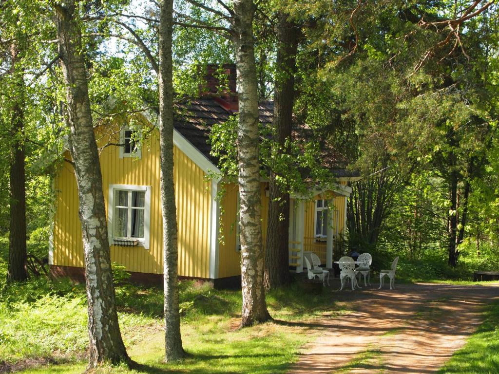 a yellow house in the middle of trees at Tammiston Cottages in Naantali