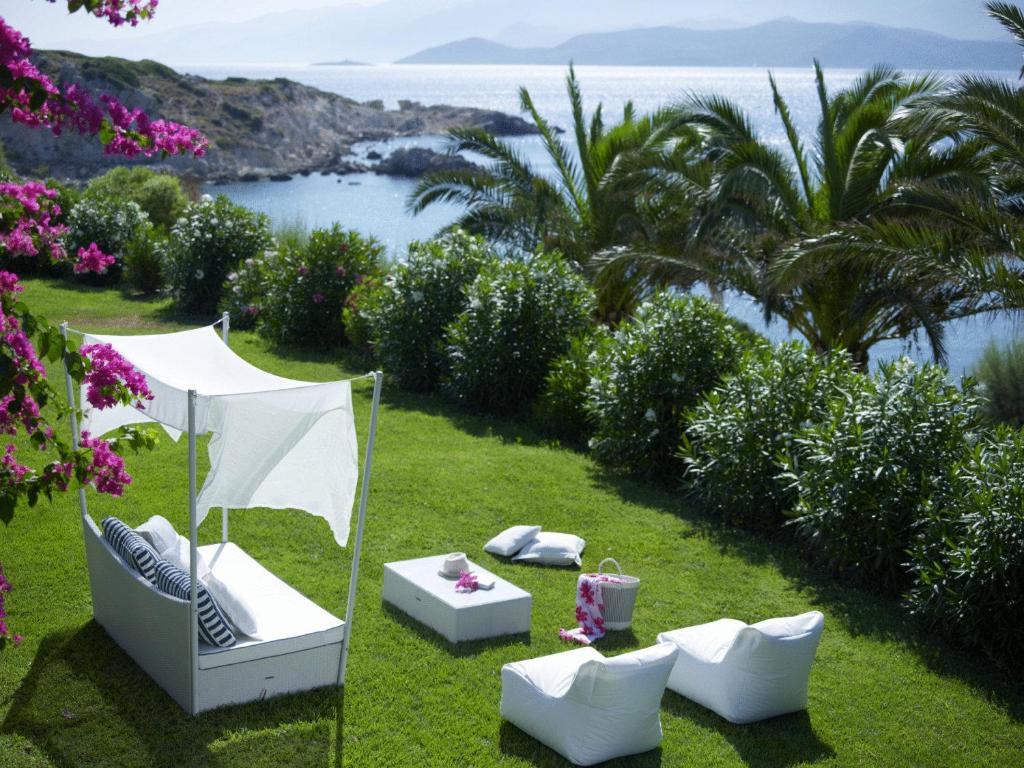 a garden with white furniture and a view of the ocean at Proteas Blu Resort in Pythagoreio