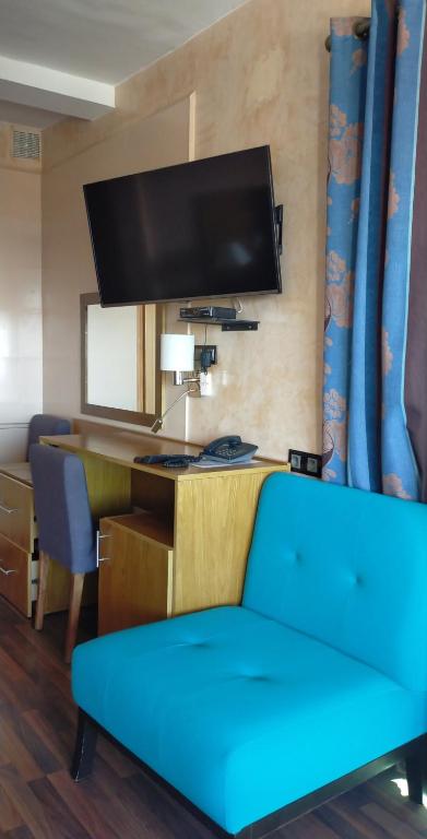 a living room with a blue couch and a desk at Studiotel Afoud in Agadir
