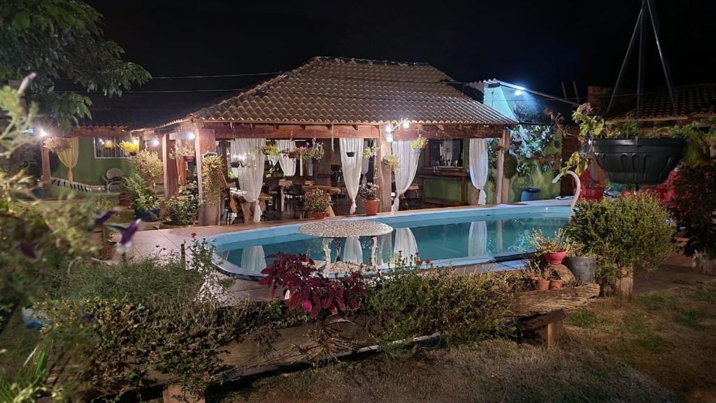 a house with a swimming pool at night at Pousada Cantinho de Casa in Nobres