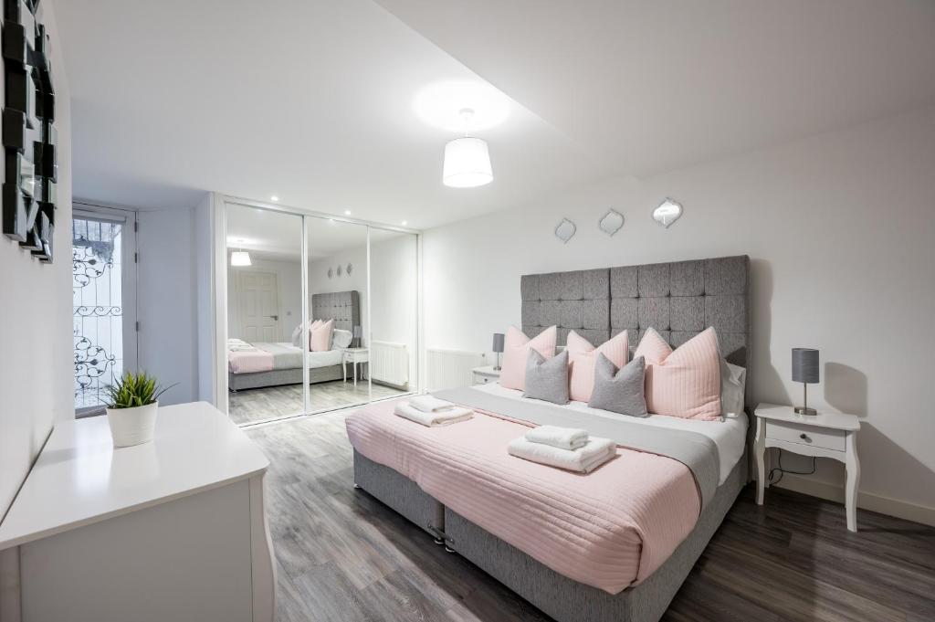 a bedroom with a large bed with pink pillows at Casa Fresa - King Street Apartments in Dundee