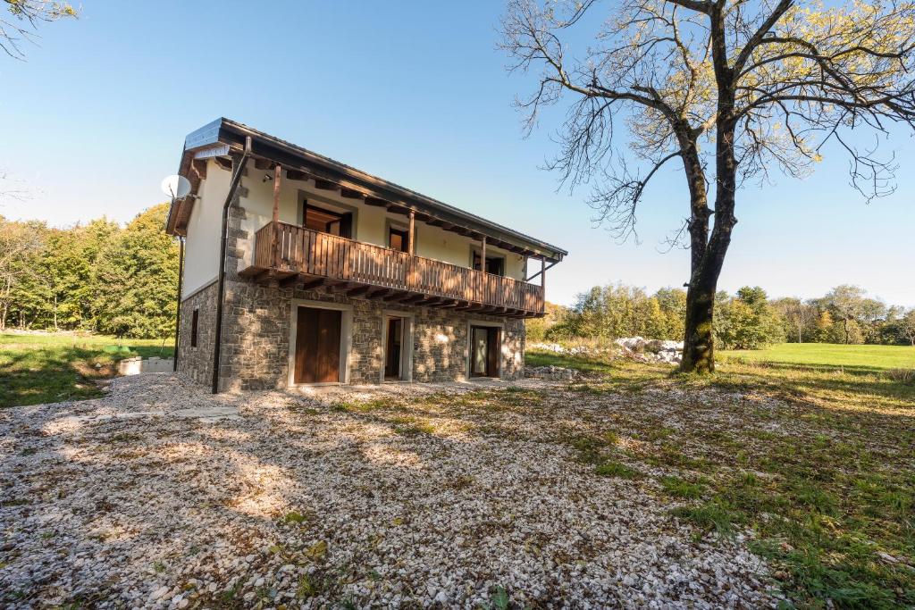 una vieja casa de piedra en un campo con un árbol en Albergo Diffuso Forgaria Monte Prat, en Forgaria nel Friuli