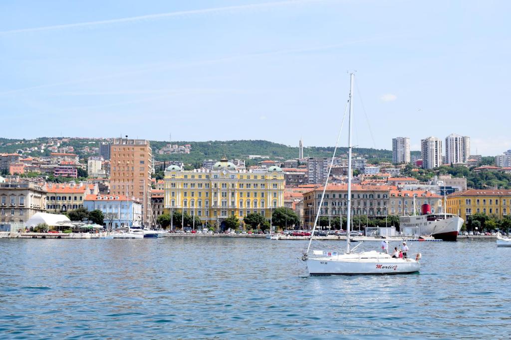 un voilier dans l'eau devant une ville dans l'établissement Apartment Duxiana with garden, à Rijeka