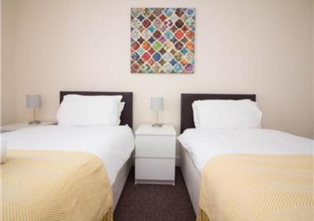 Habitación con 2 camas y una pintura en la pared. en StayZo Penthouse Accommodation 2- Premier Lodge, en Southampton