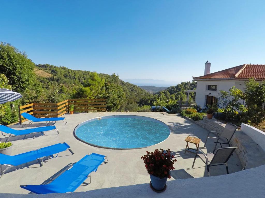 a swimming pool with blue lounge chairs and a house at Kastanies Country House in Skopelos Town