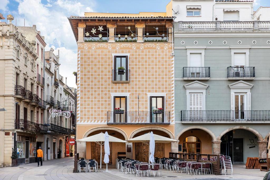 um edifício com mesas e guarda-sóis numa rua da cidade em Cal Roure Boutique Hotel em Igualada