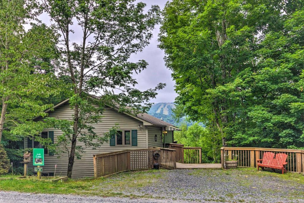 una casa en el bosque con una terraza y una casa en Warm Wooded Cabin with 2-Story Deck and Mountain View!, en Beech Mountain