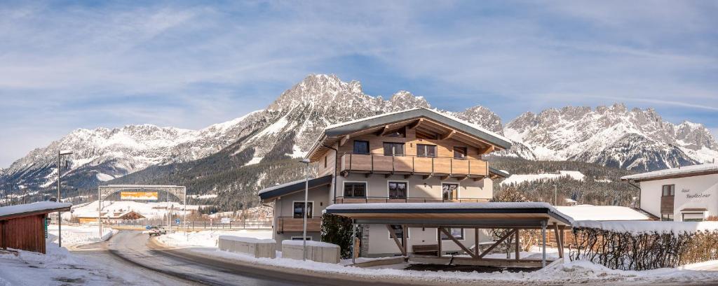 a building with snow covered mountains in the background at Haus Kathi in Ellmau