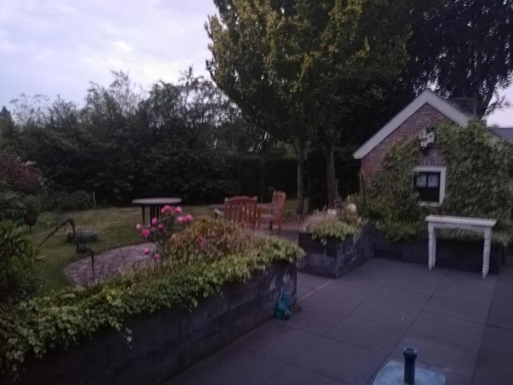 un patio trasero con un banco, una mesa y flores en De Lindehoeve Appartement de Pompestraat, en Vledder