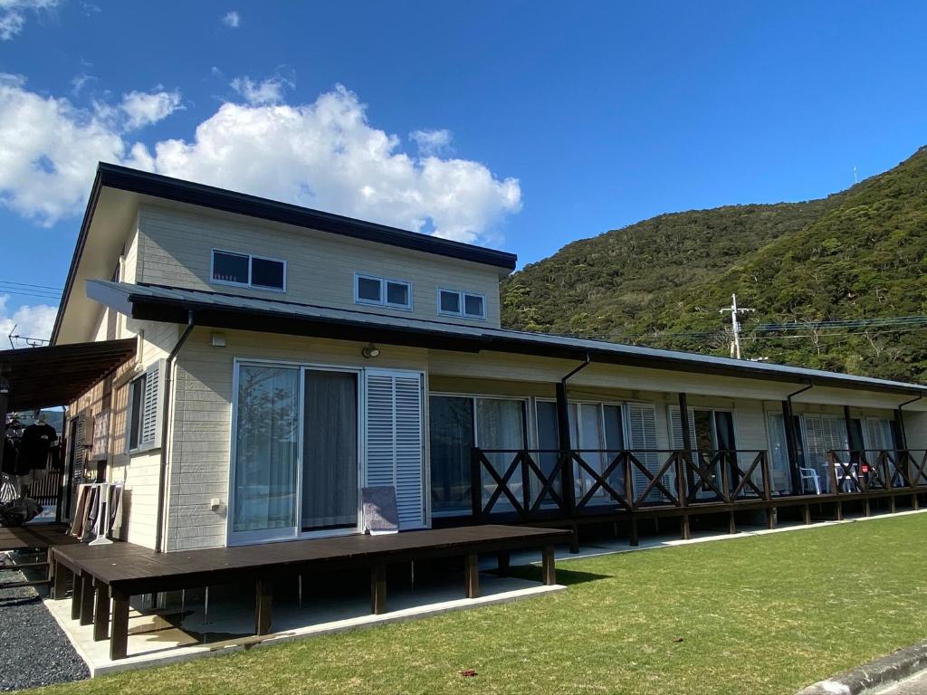 a house with a large porch with a bench at 海が見えるゲストハウス　浜んちゅ in Yamato