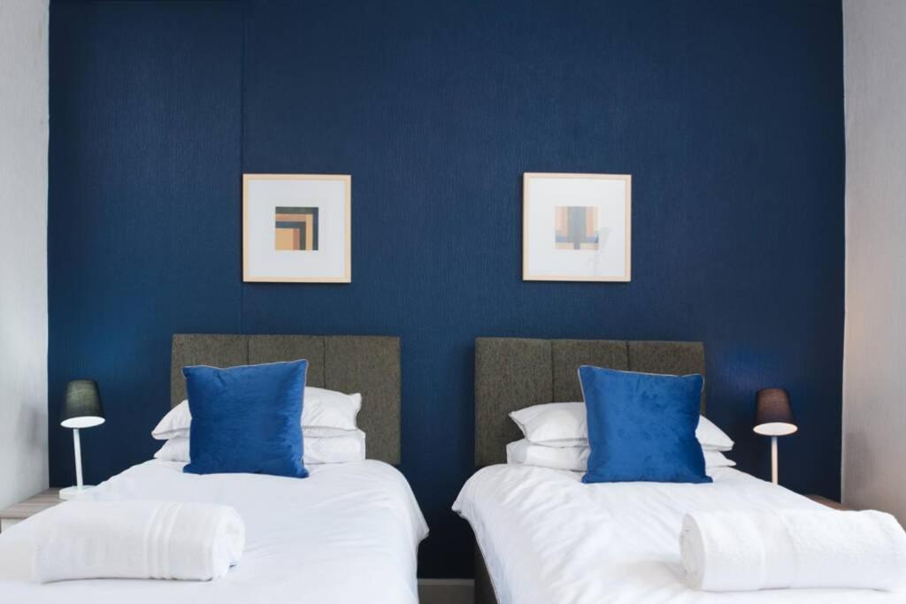 2 camas en una habitación con paredes azules en Newport house sleeps 9 - Mycityhaven en Newport