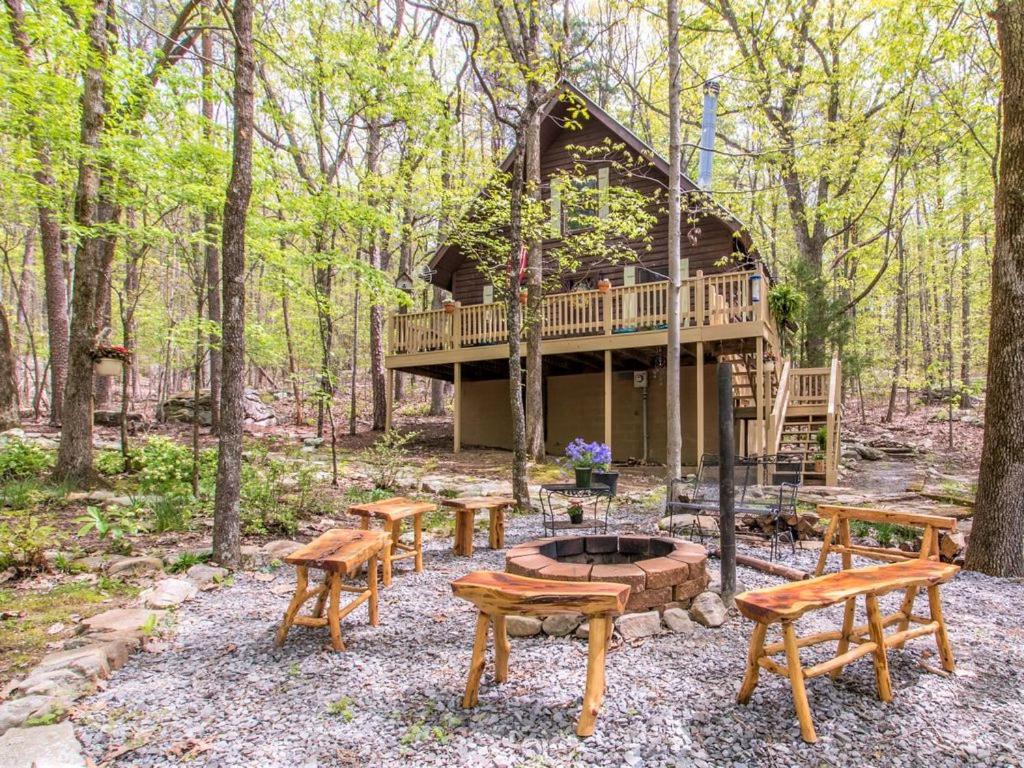 uma cabana na floresta com bancos e uma fogueira em Birds Eye View Chalet em Mentone