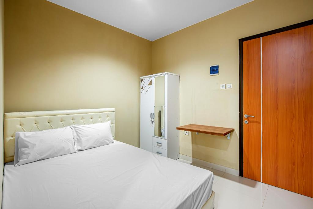 a bedroom with a white bed and a wooden door at Tami House Bintaro Syariah in Tangerang