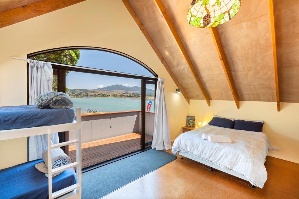 a bedroom with a bed and a large window at Raglan Backpackers in Raglan