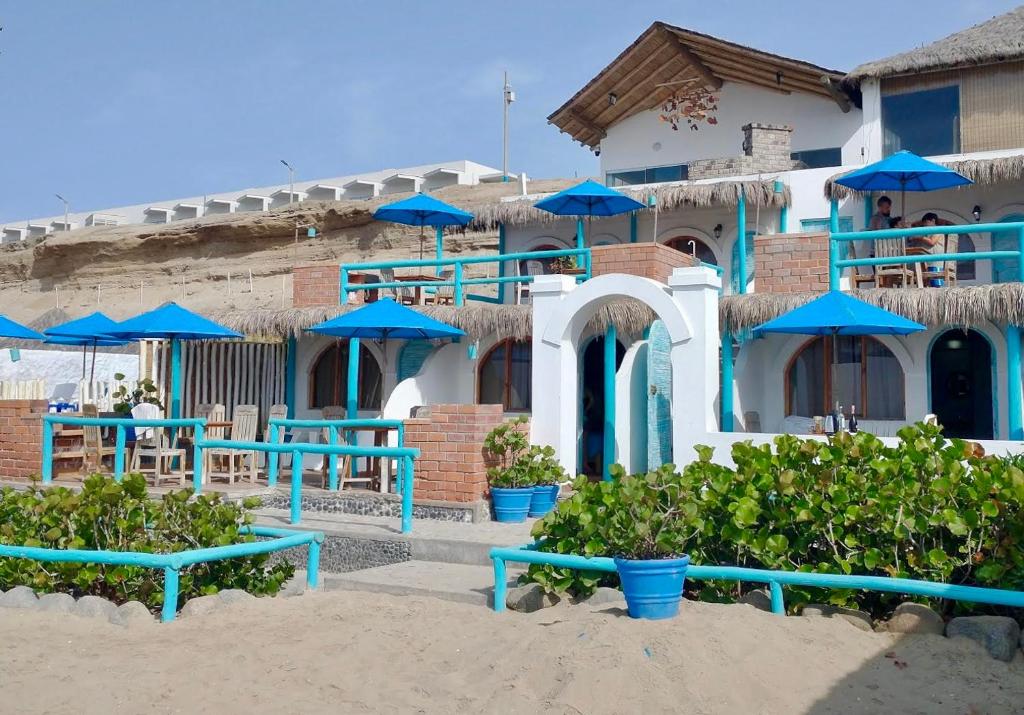 a building with blue tables and blue umbrellas at Hamacas in Punta Negra