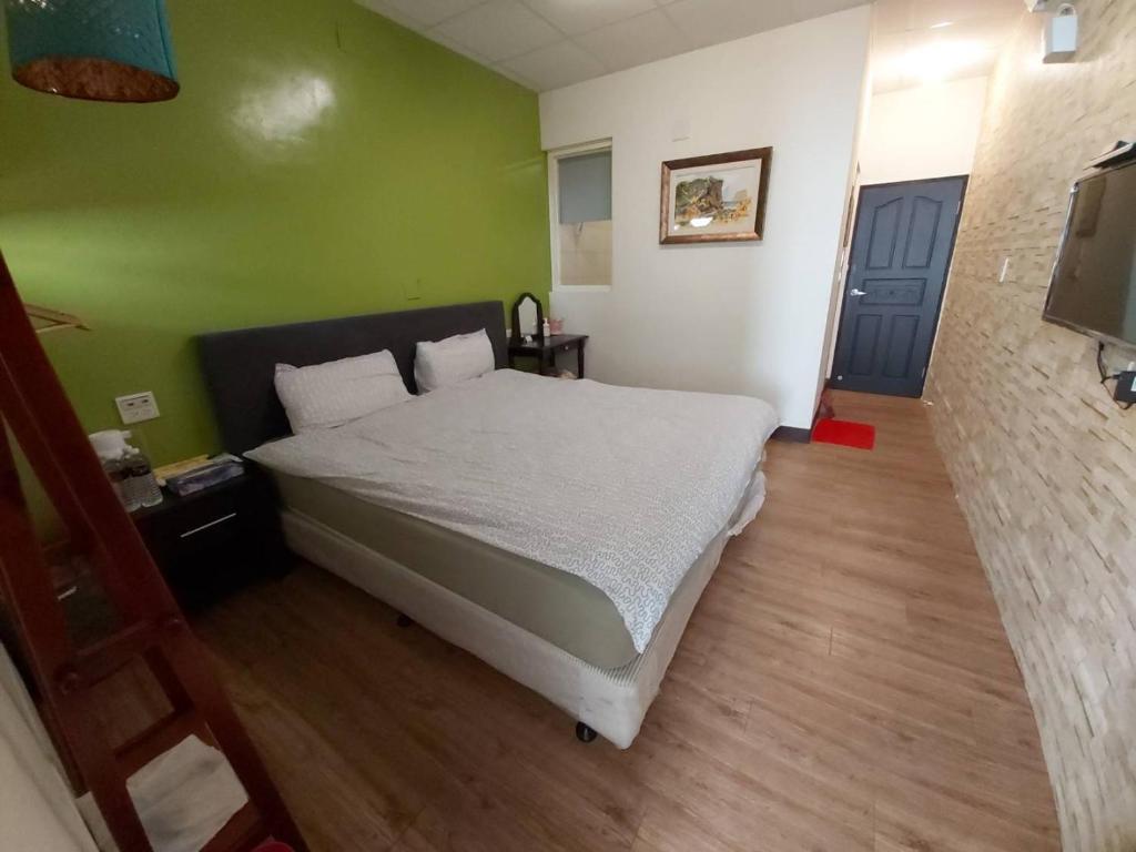 ein Schlafzimmer mit einem Bett und einer grünen Wand in der Unterkunft 稻禾民宿 