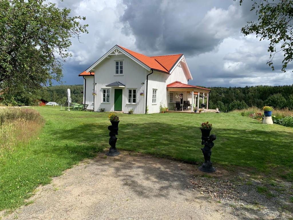 una casa blanca con techo naranja en el césped en Rustic luxury lakeside house transformed chapel, en Töcksfors