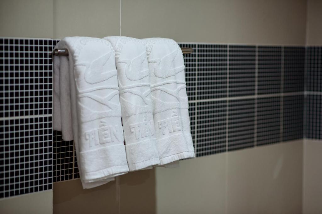 Un baño con toallas blancas colgando de un toallero. en Song Tien Hotel en My Tho