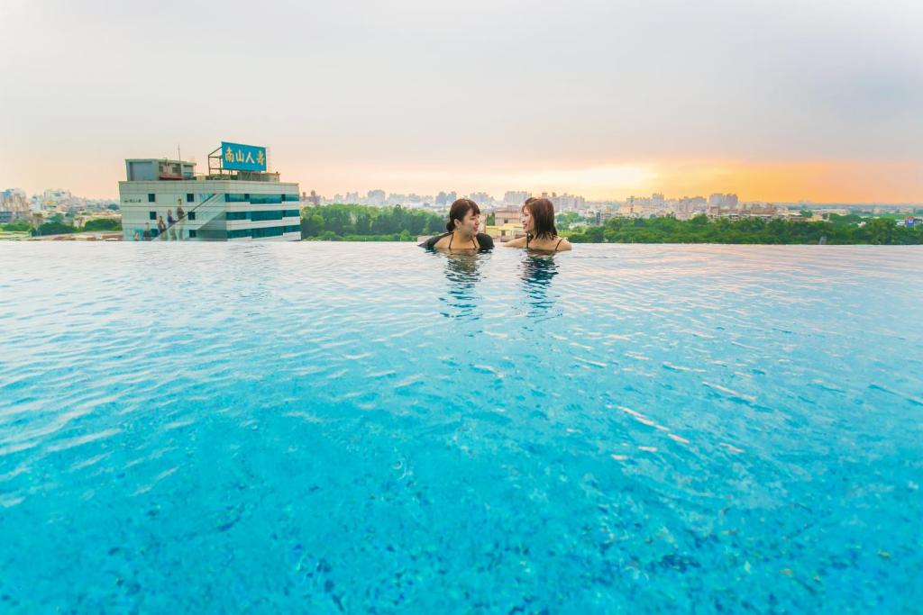 twee vrouwen in het overloopzwembad van een hotel bij Hotel Day Plus Teascape in Chiayi City