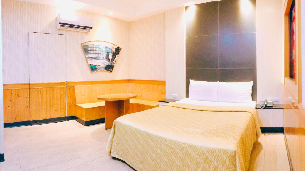 Dormitorio pequeño con cama y mesa en 楓情汽車旅館 en Pingtung City