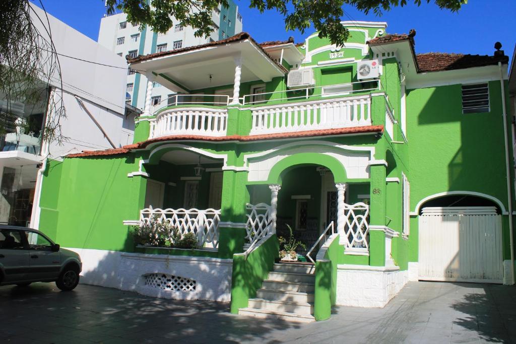 a green house with a white balcony on a street at Pousada Beira Mar in Santos