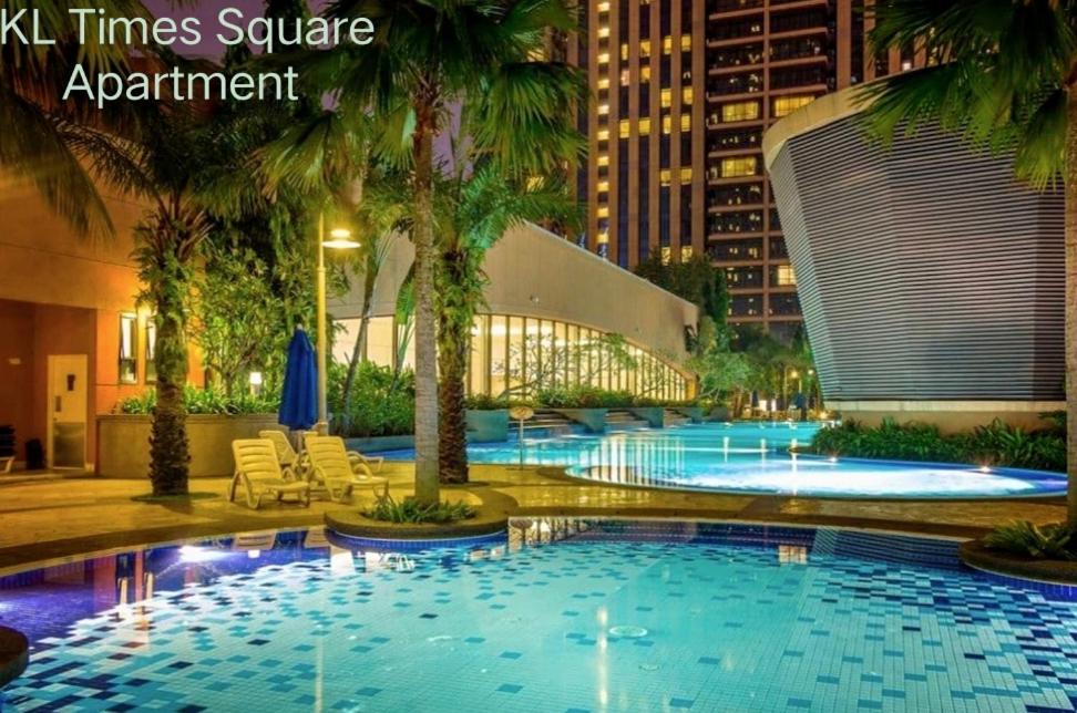 a large swimming pool with palm trees and a building at KL Times Square Apartment in Kuala Lumpur