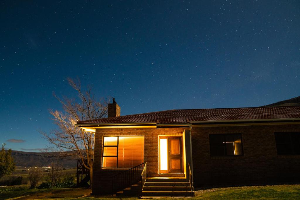 une maison avec des lumières sur son côté la nuit dans l'établissement Boplaas Guesthouse, à Op-die-Berg