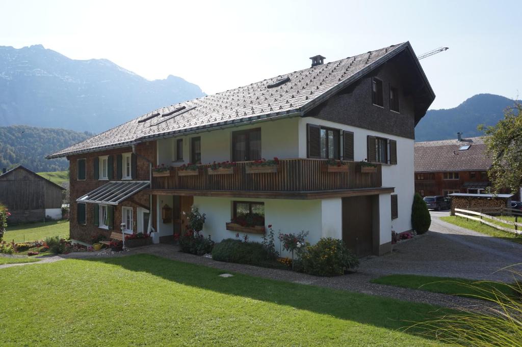 a large house with a balcony and a yard at Gästehaus Metzler in Bizau