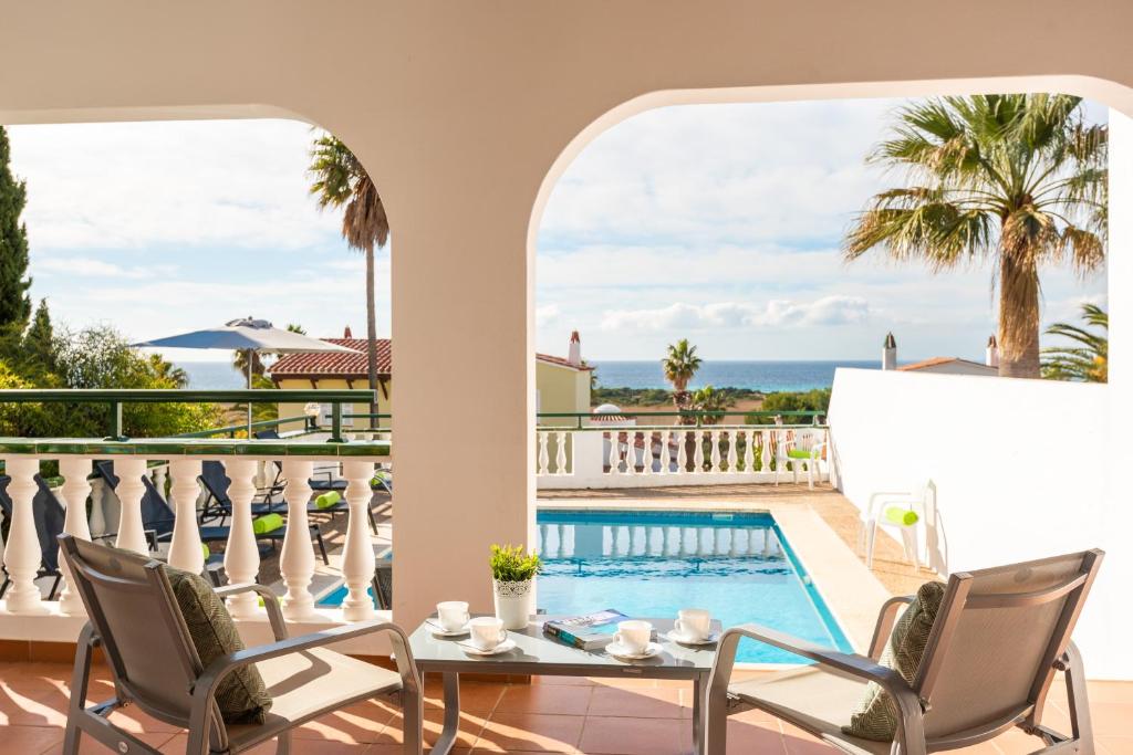 a patio with a table and chairs and a swimming pool at Villa Carolina in Son Bou