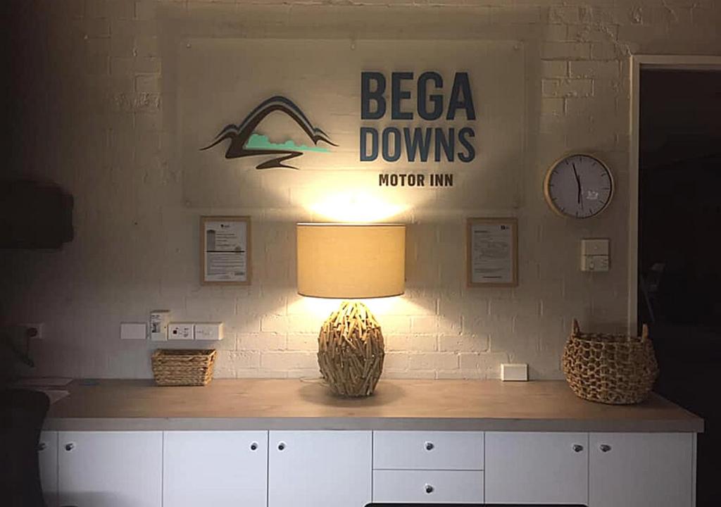 a table with a lamp and a sign on a wall at Bega Downs Motor Inn in Bega