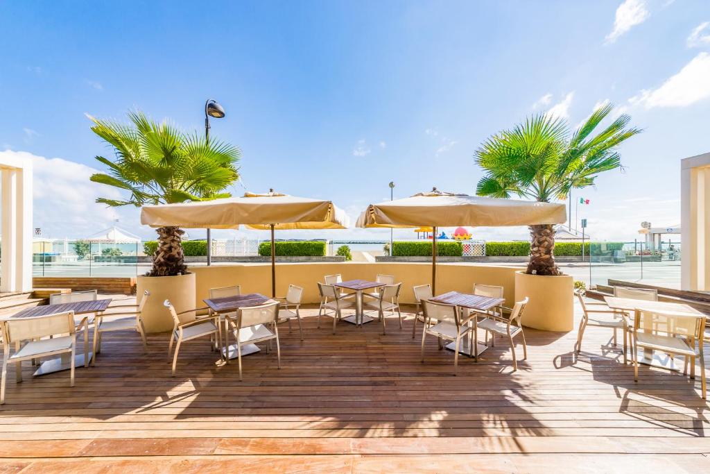eine Terrasse mit Tischen, Stühlen und Sonnenschirmen in der Unterkunft Hotel Agostini in Bellaria-Igea Marina