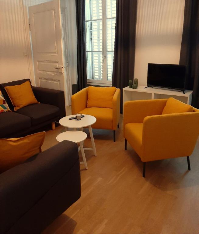 Una sala de estar con sillas amarillas y una mesa. en LE 1 &quot; GÎTES TOUT CONFORT à COLMAR CENTRE&quot;, en Colmar