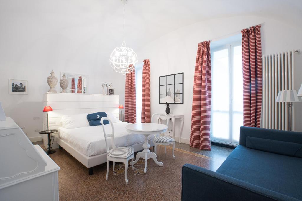 a white bedroom with a bed and a table and chairs at Hotel Marina Charming Rooms in Finale Ligure