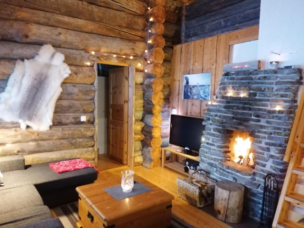 ein Wohnzimmer mit einem Kamin in einer Blockhütte in der Unterkunft Otsontupa Apartment in Ruka