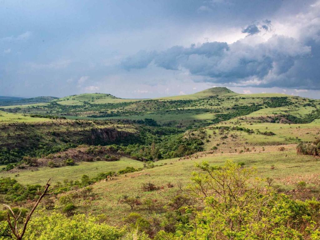 a view of green hills with clouds in the sky at Riverbed Africa in Lydenburg