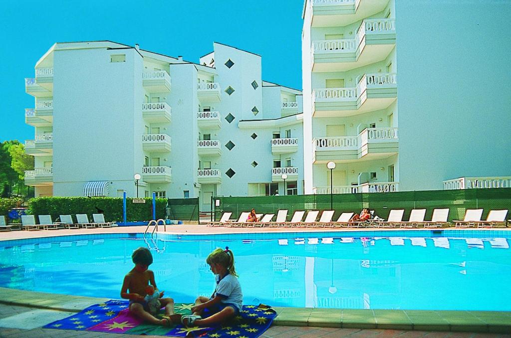 una mujer y un niño sentados junto a una piscina en Flat in Lignano, en Lignano Sabbiadoro