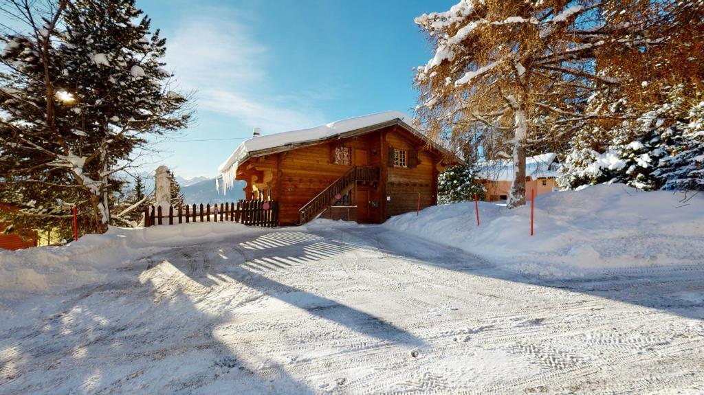 una cabaña de madera en la nieve con entrada en Apartment at the bottom of the slopes in Crans-Montana, cosy atmosphere en Crans-Montana