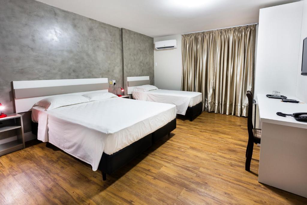 a hotel room with two beds and a desk at H Hotel in Balneário Camboriú