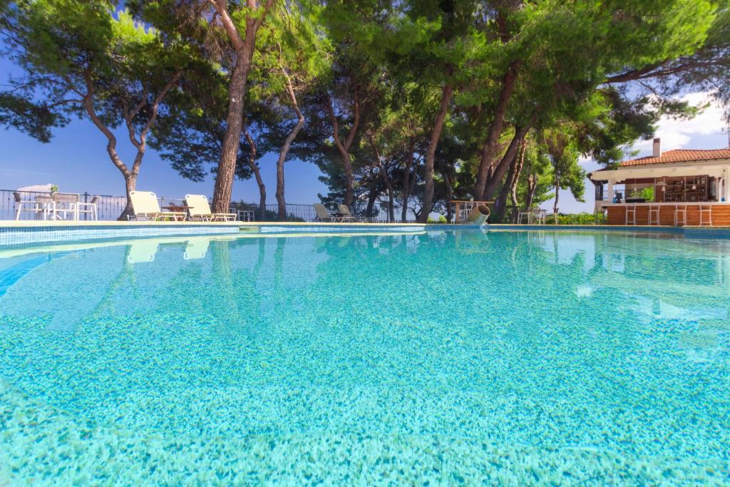 a large blue swimming pool with trees in the background at Evripidis Hotel in Afitos