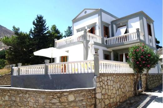 a large white house with a stone wall at Fofi Apartments in Symi