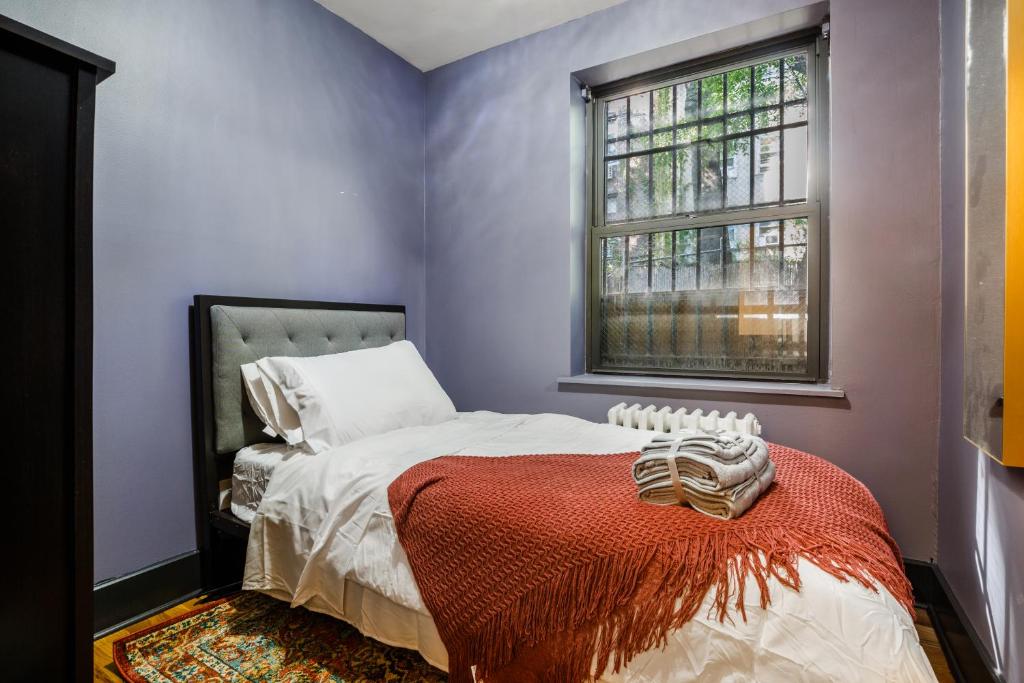 um quarto com uma cama com um cobertor vermelho e uma janela em Lamartine Chelsea em Nova York