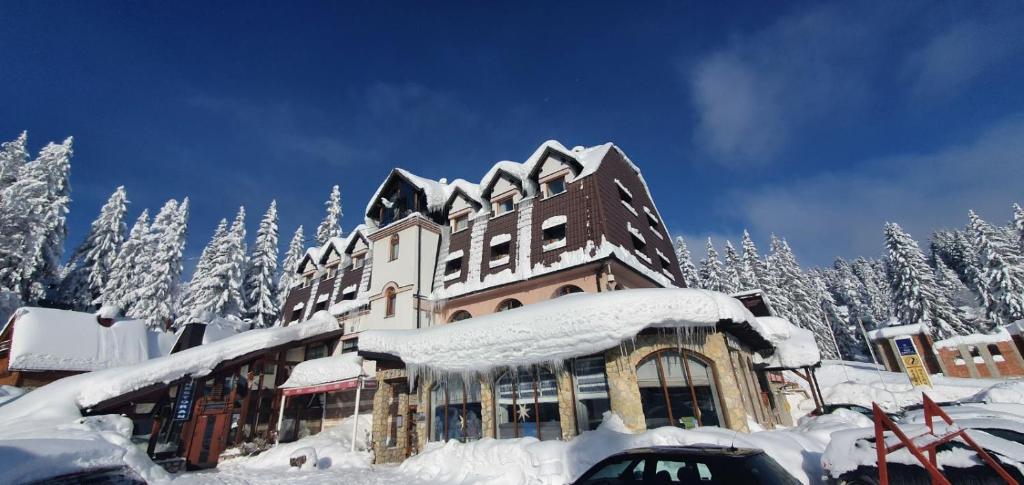 een gebouw bedekt met sneeuw en met sneeuw bedekte bomen bij Hotel Kristal in Jahorina