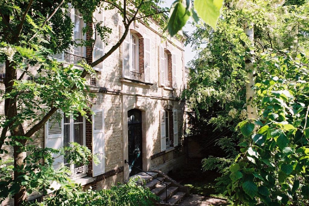 an old stone house with a door and trees at Au fil de Troyes in Sainte-Savine