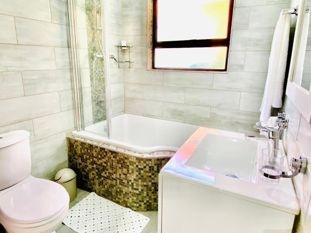 a bathroom with a tub and a toilet and a sink at C&C HOTEL VIBES Randpark Ridge JHB 14 Units Available in Boskruin