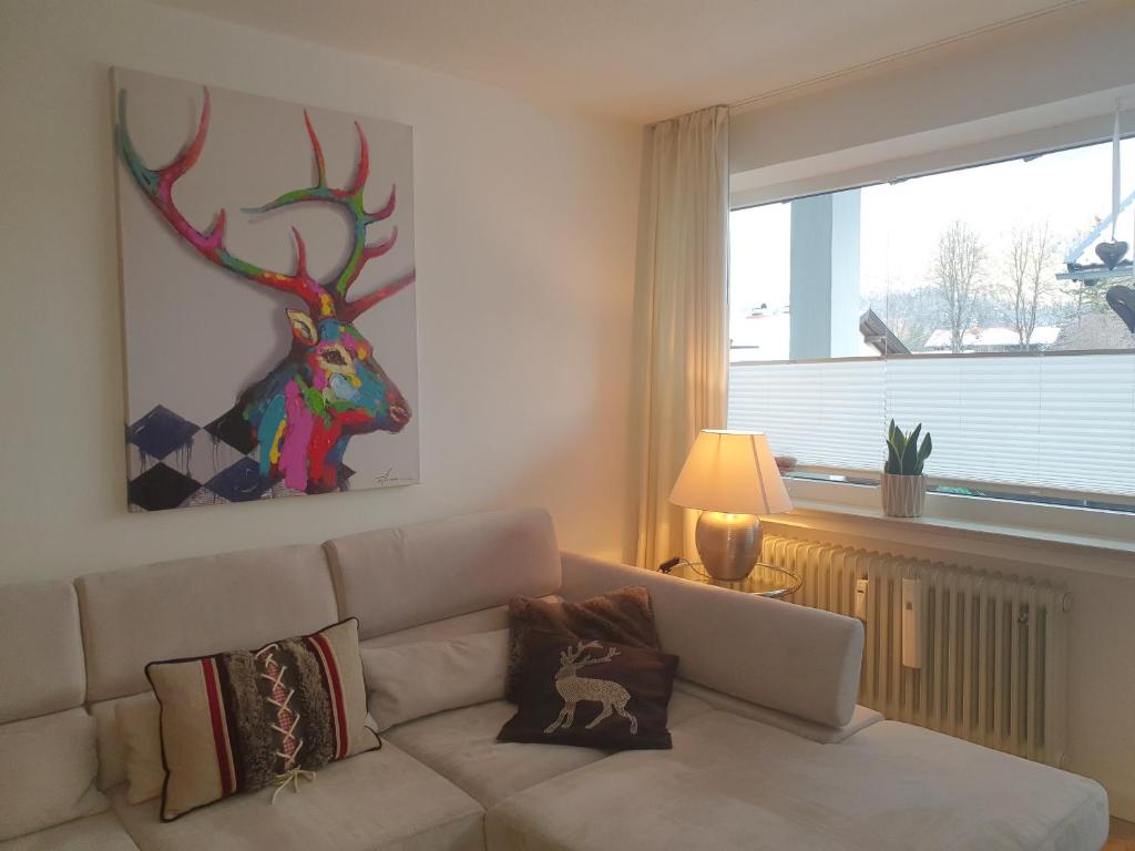 salon z kanapą i obrazem jelenia w obiekcie Fewo Schneewittchen w mieście Mittenwald