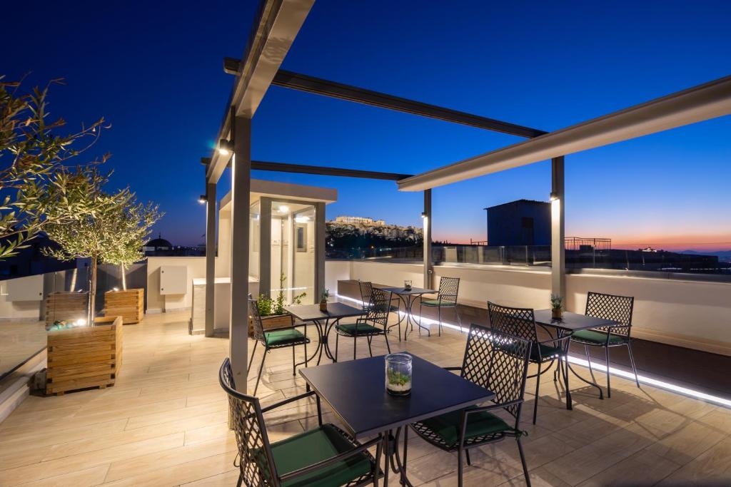 a rooftop patio with tables and chairs at night at Hestia - Romvis 9 in Athens