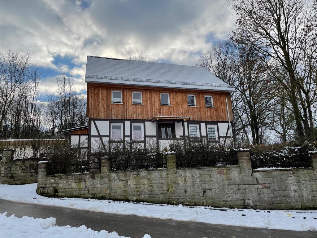 ein Holzhaus mit einem Zaun im Schnee in der Unterkunft Ferienwohnung im Hooptal in Negenborn